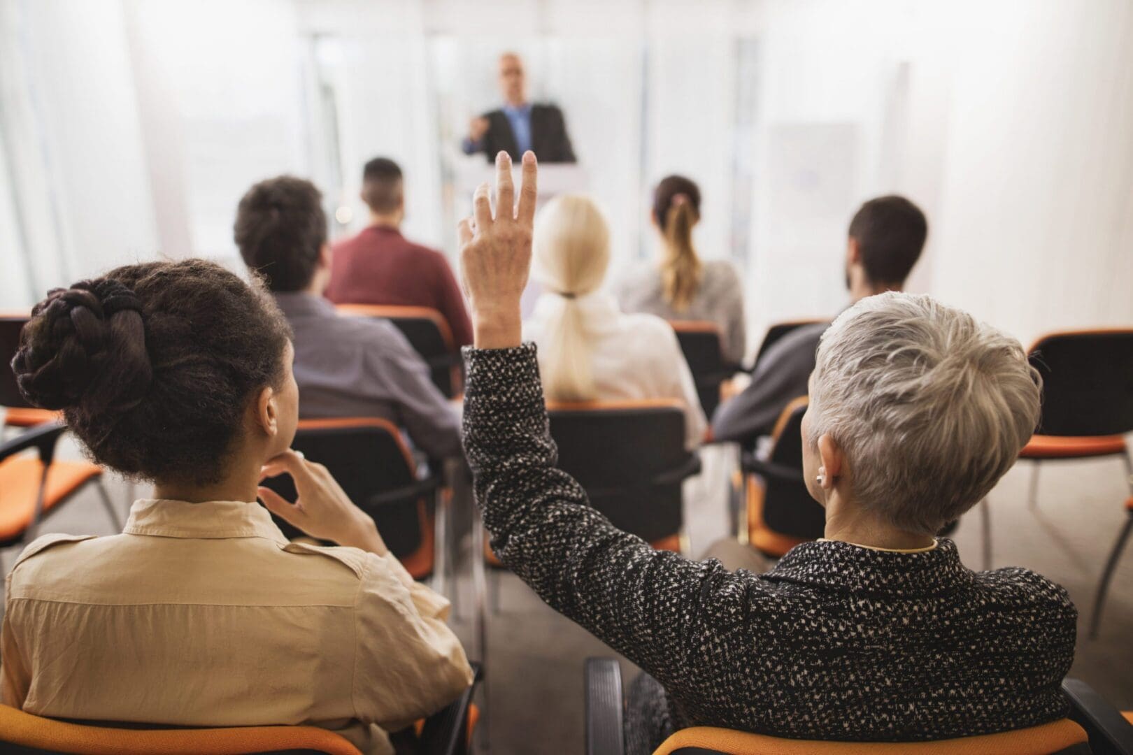 Audience member raising hand during seminar